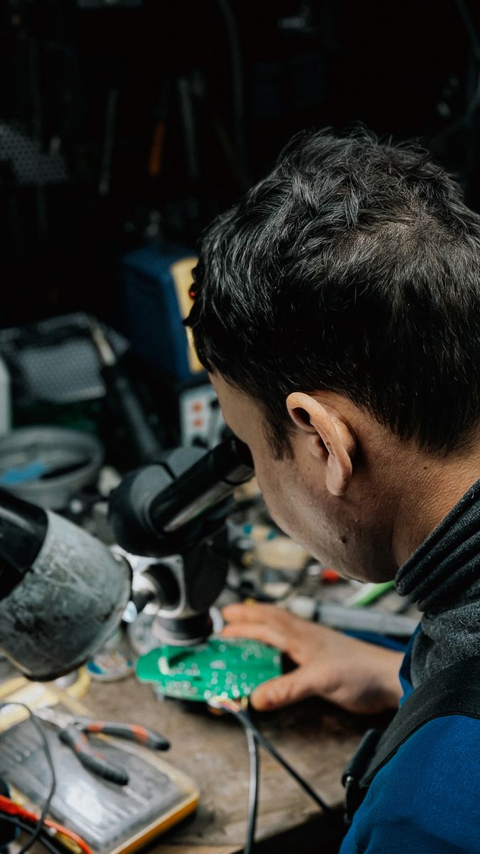 Technician inspecting a circuit board through a microscope